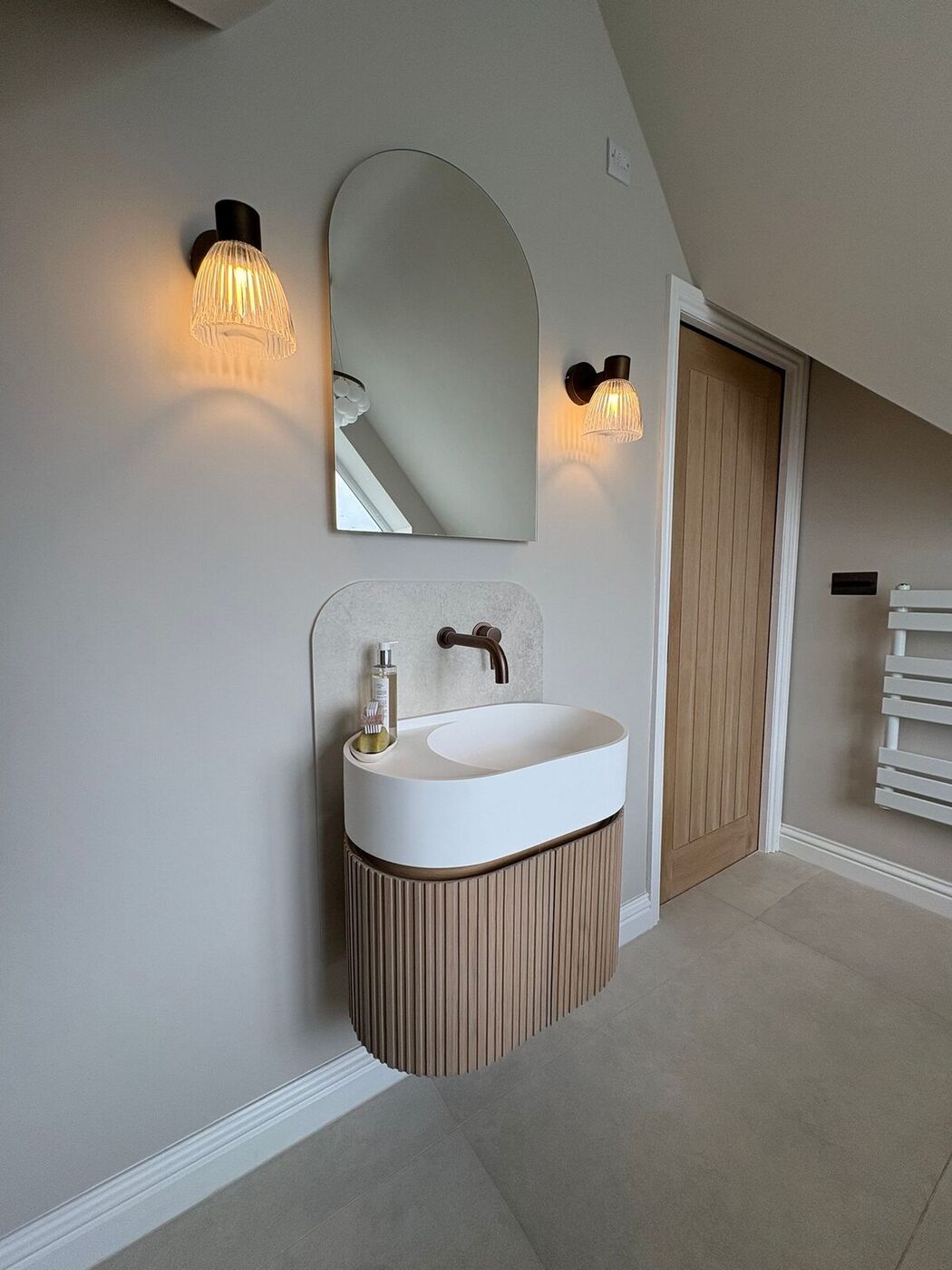 En-suite vanity with arched mirror and ribbed unit